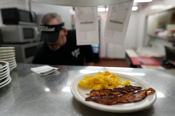 Bacon and eggs are up to serve as Chris Barton cooks at the grill at the Pepper Pod Restaurant, Thursday, Feb.13, 2025, Newport, Ky. (AP Photo/Carolyn Kaster)