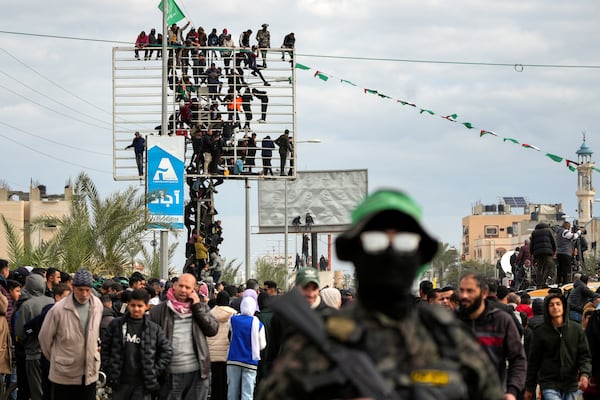 Palestinians watch as Hamas fighters deploy ahead of the hand over to the Red Cross of three Israeli hostages as part of the Gaza ceasefire deal with Israel in Deir Al-Balah, central Gaza Strip, Saturday Feb. 8, 2025. (AP Photo/Abdel Kareem Hana)