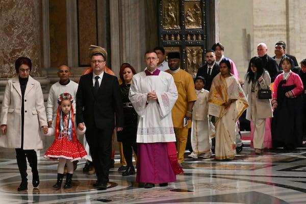 The first pilgrims pass through after Pope Francis opened the Holy Door to mark the opening of the 2025 Catholic Holy Year, or Jubilee, in St. Peter's Basilica, at the Vatican, Tuesday Dec. 24, 2024. (Alberto Pizzoli/Pool via AP)