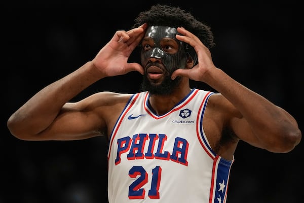 Philadelphia 76ers' Joel Embiid (21) adjusts his mask during the first half of an NBA basketball game against the Brooklyn Nets Saturday, Jan. 4, 2025, in New York. (AP Photo/Frank Franklin II)