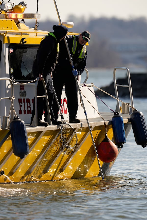 Members of a Fire and Rescue team search for debris on the Potomac river, Saturday, Feb. 1, 2025, in Alexandria, Va., near the wreckage site where an American Airlines jet and a Black Hawk helicopter collided. (AP Photo/Carolyn Kaster)