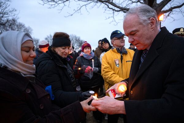 Sen. Tim Kaine, D-Va., right, lights candle at the start of a candlelight vigil, Wednesday, Feb. 5, 2025 in Alexandria, Va., for the victims of the mid-air collision of an American Airlines jet and a Black Hawk helicopter at Reagan National Airport. (AP Photo/Kevin Wolf)