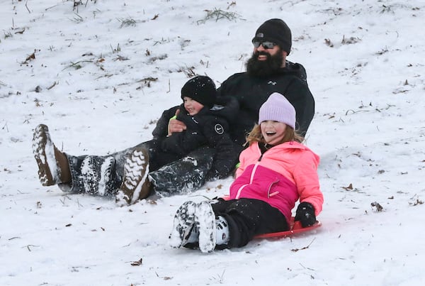 Mackenzie Smith, 9, wins a race against her brother, Landon Smith, 3, and her father, Ryan Smith, as they sled down the hill behind Chautauqua Park during the second day of a winter storm in Owensboro, Ky., on Monday, Jan. 6, 2025. (Alan Warren/The Messenger-Inquirer via AP)