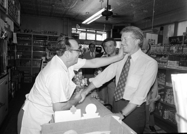 FILE - Democratic presidential candidate Jimmy Carter gets a pinch on the cheek as he greets Charlie Lanzaro, left, at a Queens, N.Y., delicatessen, Aug. 31, 1976. Carter had just arrived in New York on a campaign swing. (AP Photo/Peter Bregg, File)