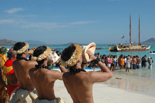 FILE - Men blow conch shells to welcome the Hokulea voyaging canoe into Kailua Bay in Kailua, Hawaii, May 1, 2005. (AP Photo/Ronen Zilberman, File)