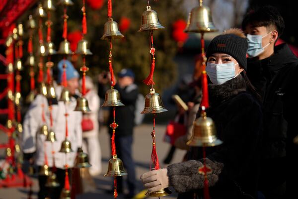 A woman touches bells for luck as people gather at the Ditan Temple Fair on the first day of the Chinese Lunar New Year in Beijing on Wednesday, Jan. 29, 2025. (AP Photo/Aaron Favila)