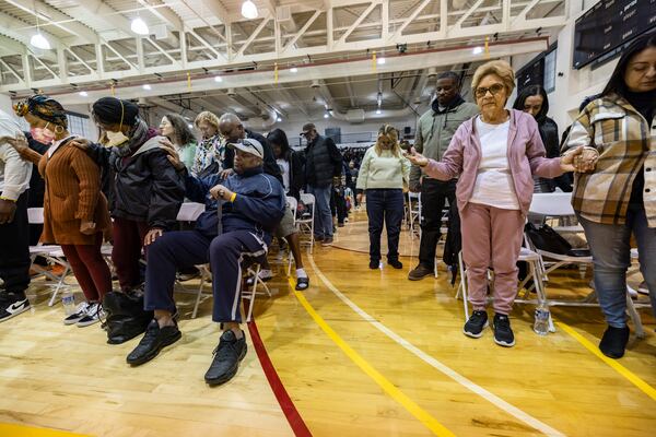 People impacted by the Eaton Fire pray as they attend an event at the gymnasium of Pasadena City College where The Change Reaction will be handing out about 1,000 checks of between $2,500-$5,000, Tuesday, Jan. 28, 2025 in Pasadena, Calif. (AP Photo/Etienne Laurent)