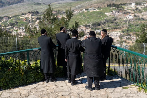 Ultra-Orthodox Jewish men look from Kibbutz Misgav Am in northern Israel at the village of Odaisseh in Southern Lebanon after Israeli forces withdrew from border villages , Tuesday, Feb. 18, 2025. (AP Photo/Ariel Schalit)