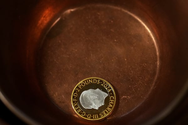 A two Pound gold coin lies in the approved copper bowl during the "Trial of the Pyx,'' a ceremony that dates to the 12th Century in which coins are weighed in order to make certain they are up to standard, at the Goldsmiths' Hall in London, Tuesday, Feb. 11, 2025.(AP Photo/Frank Augstein)