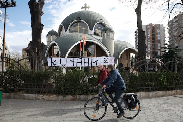 A cyclist goes past a banner reads: "Kocani" hanging from a fence outside the St. Clement Christian Orthodox church in Skopje, North Macedonia, Monday, March 17, 2025, following a massive fire in the nightclub in the town of Kocani, early Sunday. (AP Photo/Boris Grdanoski)