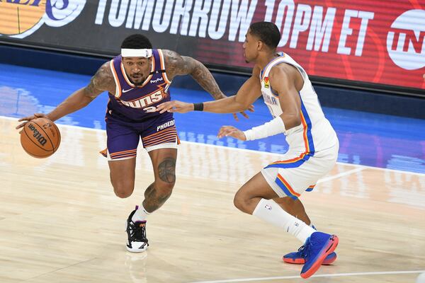 Phoenix Suns guard Bradley Beal, left, drives past Oklahoma City Thunder guard Aaron Wiggins, right, during the first half of an NBA basketball game, Wednesday, Feb. 5, 2025, in Oklahoma City. (AP Photo/Kyle Phillips)