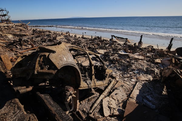 A burned car is seen among debris in the wreckage of a home destroyed by the Palisades Fire, Tuesday, Jan. 14, 2025, in Malibu, Calif. (AP Photo/Ethan Swope)