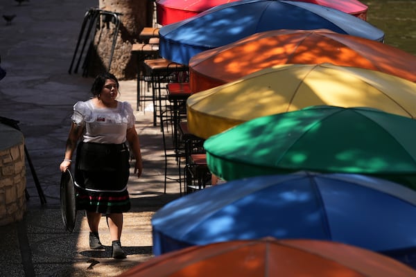 A waitress tends to outdoor patrons as temperatures top the triple-digit mark, Tuesday, May 13, 2025, in San Antonio. (AP Photo/Eric Gay)