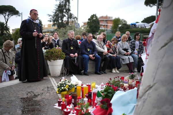 Archbishop Paolo Pezzi, standing at left, leads a rosary with a group of pilgrims from Moscow, Russia, at Agostino Gemelli Polyclinic, in Rome, Tuesday, March 11, 2025 where Pope Francis is hospitalized since Friday, Feb. 14. (AP Photo/Alessandra Tarantino)