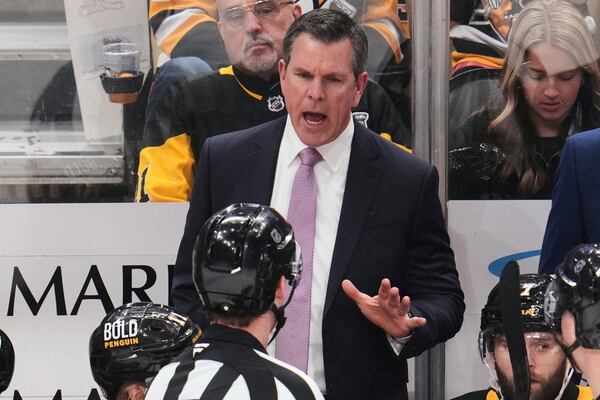 Pittsburgh Penguins head coach Mike Sullivan talks with referee Brandon Schrader during the third period of an NHL hockey game against the Washington Capitals in Pittsburgh, Thursday, April 17, 2025. (AP Photo/Gene J. Puskar)