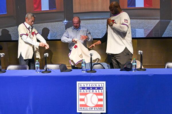 Newly-elected Baseball Hall of Fame members, from left, Ichiro Suzuki, Billy Wagner and CC Sabathia put on their jersey and caps during a news conference, Thursday, Jan. 23, 2025, in Cooperstown, N.Y. (AP Photo/Hans Pennink)