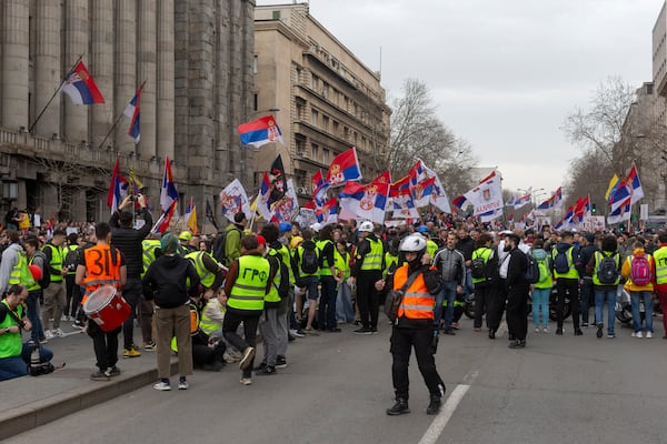 Protesters block a street while waving Serbian flags during a major anti-corruption rally led by university students in Belgrade, Serbia, Saturday, March 15, 2025. (AP Photo/Marko Drobnjakovic)