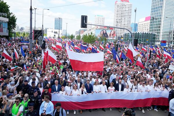 The liberal presidential candidate Rafal Trzaskowski holds a giant polish flag in the first row as he stands next to a waving women during a march one week ahead of a decisive presidential election in Warsaw, Poland on Sunday, May 25, 2025. (AP Photo/Czarek Sokolowski)