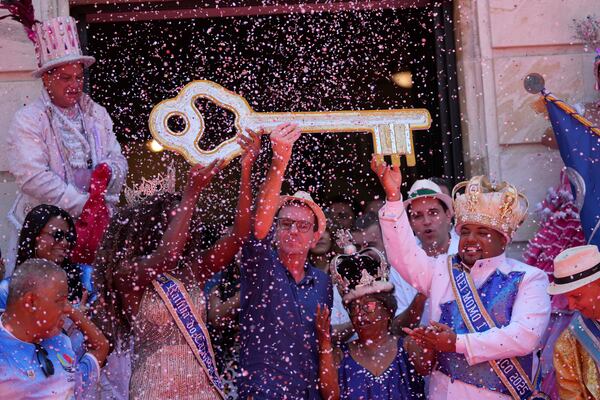 Carnival King Momo, Kaio Mackenzie, right, with Queen Thuane de Oliveira, hold up the keys of the city from Mayor Eduardo Paes, center, at a ceremony officially kicking off Carnival in Rio de Janeiro, Brazil, Friday, Feb. 28, 2025. (AP Photo/Silvia Izquierdo)