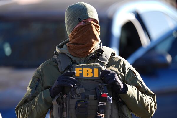 An agent from the Federal Bureau of Investigation stands watch outside an apartment complex during a raid Wednesday, Feb. 5, 2025, in east Denver. (AP Photo/David Zalubowski)