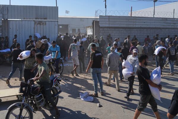 Palestinians carry bags of flour after storming a U.N. World Food Program warehouse in Zawaida, Central Gaza Strip, on Wednesday, May 28, 2025. (AP Photo/Abdel Kareem Hana)