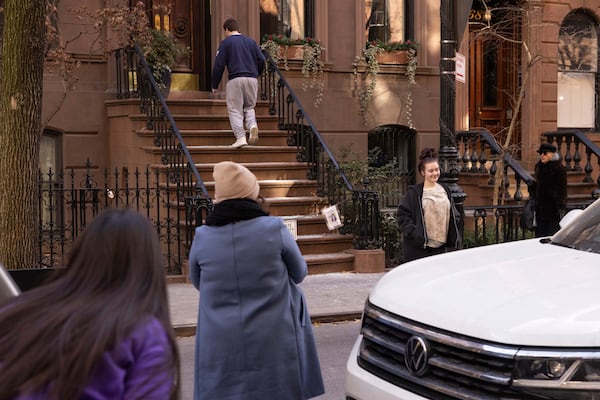 People gather to take selfies outside the brownstone where Carrie Bradshaw lived in “Sex and the City”, in New York, Wednesday, Jan. 15, 2025. The city’s Landmarks Preservation Commission approved an application for a metal gate for the front staircase of the Manhattan brownstone to keep away tourists who endlessly trespass and pose for pictures. (AP Photo/Yuki Iwamura)