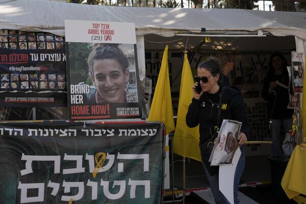 A woman walks past a photo of Arbel Yehoud, and a banner in Hebrew demanding the return of the hostages held by Hamas in Gaza Strip at the entrance of a tent set up in Jerusalem, Monday, Jan. 27, 2025. (AP Photo/Mahmoud illean)