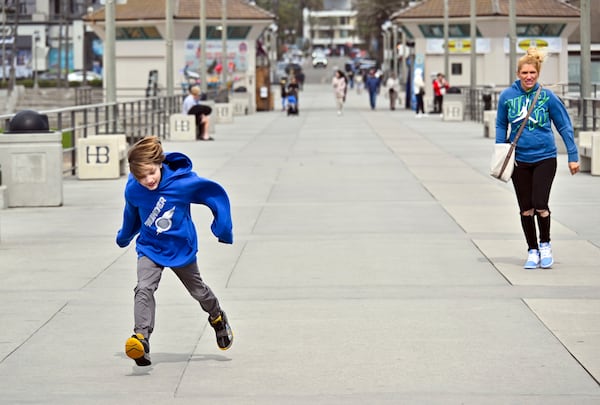 Hudson Kammarcal, 8, runs in the wind as his mother, Heidi Kammarcal, of Coeur d'Alene, Idaho, tries to keep up on the pier in Huntington Beach, Calif., Thursday, March 13, 2025, after strong storms moved through the region overnight. (Jeff Gritchen/The Orange County Register via AP)