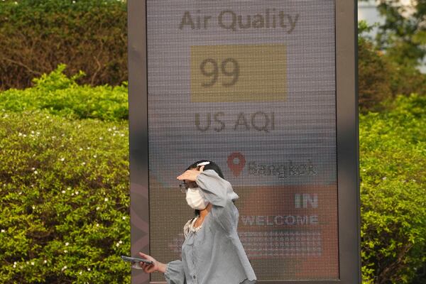 FILE - A pedestrian wears a face mask in front of a sign displaying Air Quality Index in Bangkok, Thailand, on Feb. 6, 2025. (AP Photo/Sakchai Lalit, File)