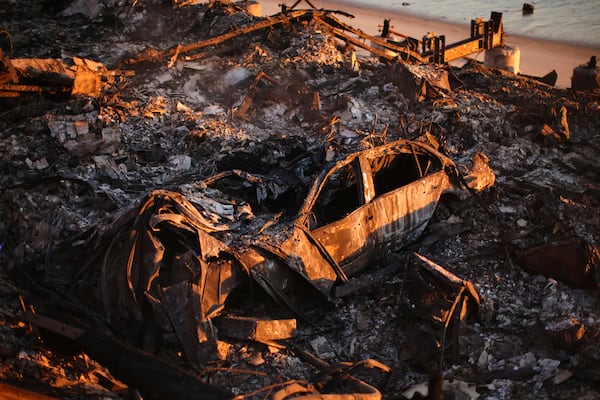 A burnt car is seen among the wreckage of a home destroyed by the Palisades Fire, Tuesday, Jan. 14, 2025, in Malibu, Calif. (AP Photo/Ethan Swope)