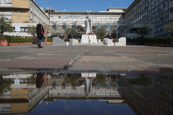 The statue of Pope John Paul II in front of the Agostino Gemelli Polyclinic is reflected in a puddle, in Rome, Thursday, Feb. 20, 2025, as the Pontiff is hospitalised since Friday, Feb. 14. (AP Photo/Alessandra Tarantino)