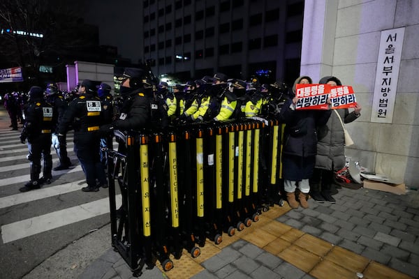 Supporters of impeached South Korean President Yoon Suk Yeol, hold signs with a message that translates to; "Release the president", alongside police officers, outside the Western District Court in Seoul, South Korea, Sunday, Jan. 19, 2025. (AP Photo/Ahn Young-joon)