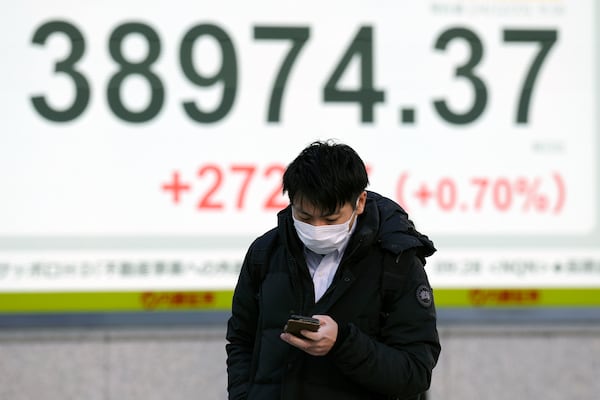 A person walks in front of an electronic stock board showing Japan's Nikkei index at a securities firm Monday, Dec. 23, 2024, in Tokyo. (AP Photo/Eugene Hoshiko)