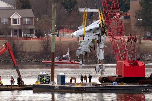 Rescue and salvage crews with cranes pull up the wreckage of an American Airlines jet in the Potomac River from Ronald Reagan Washington National Airport, Monday, Feb. 3, 2025, in Arlington, Va. (AP Photo/Jose Luis Magana)