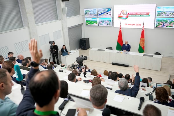 Belarusian President Alexander Lukashenko, background, speaks to the media after voting in presidential elections in Minsk, Belarus, Sunday, Jan. 26, 2025. (AP Photo/Pavel Bednyakov)