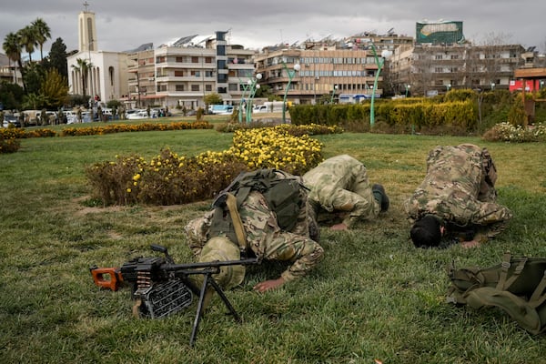 Members of the armed forces and former rebels, who overthrew Bashar Assad's government and now serve in the new Syrian government, pray before a military parade in downtown Damascus, Syria, Friday, Dec. 27, 2024. (AP Photo/Leo Correa)