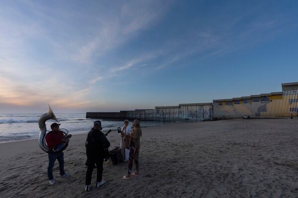 A band serenades two women near where the border wall separating Mexico and the United States reaches the Pacific Ocean Monday, Jan. 20, 2025, in Tijuana, Mexico. (AP Photo/Gregory Bull)