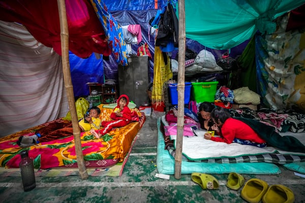 A Meitei woman and children take rest in a relief camp in Imphal, Manipur, Monday, Dec. 16, 2024. (AP Photo/Anupam Nath)