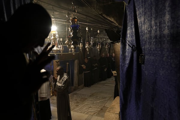 Priests pray in the Church of the Nativity, where Christians believe Jesus Christ was born, ahead of Christmas in the West Bank city of Bethlehem, Tuesday, Dec. 17, 2024. (AP Photo/Mahmoud Illean)