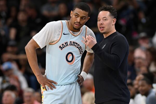 San Antonio Spurs acting head coach Mitch Johnson, right, speaks with Spurs forward Keldon Johnson during the first half of their NBA basketball game against the Cleveland Cavaliers, Friday, April 4, 2025, in San Antonio. (AP Photo/Darren Abate)