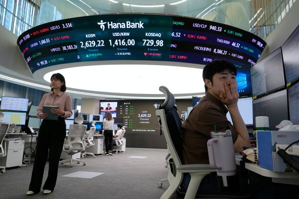 A currency trader watches monitors near a screen showing the Korea Composite Stock Price Index (KOSPI), top center left, and the foreign exchange rate between U.S. dollar and South Korean won, top center, at the foreign exchange dealing room of the KEB Hana Bank headquarters in Seoul, South Korea, Wednesday, May 14, 2025. (AP Photo/Ahn Young-joon)