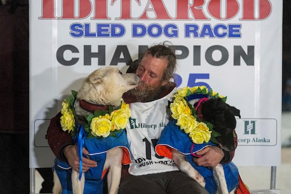 Jessie Holmes hugs his lead dogs Polar, left, and Hercules after winning the Iditarod Trail Sled Dog Race early Friday morning, March 14, 2025 in Nome. (Loren Holme/Anchorage Daily News via AP)